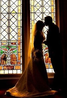 Picture of a bride and groom in front of a stained glass window